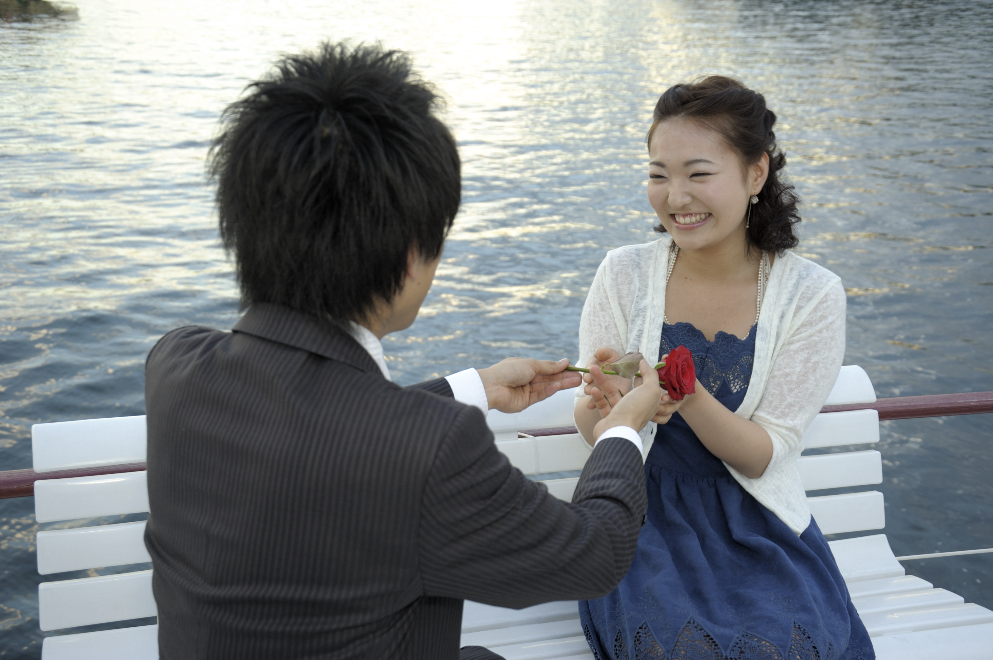 海の上でバラを差し出す男性