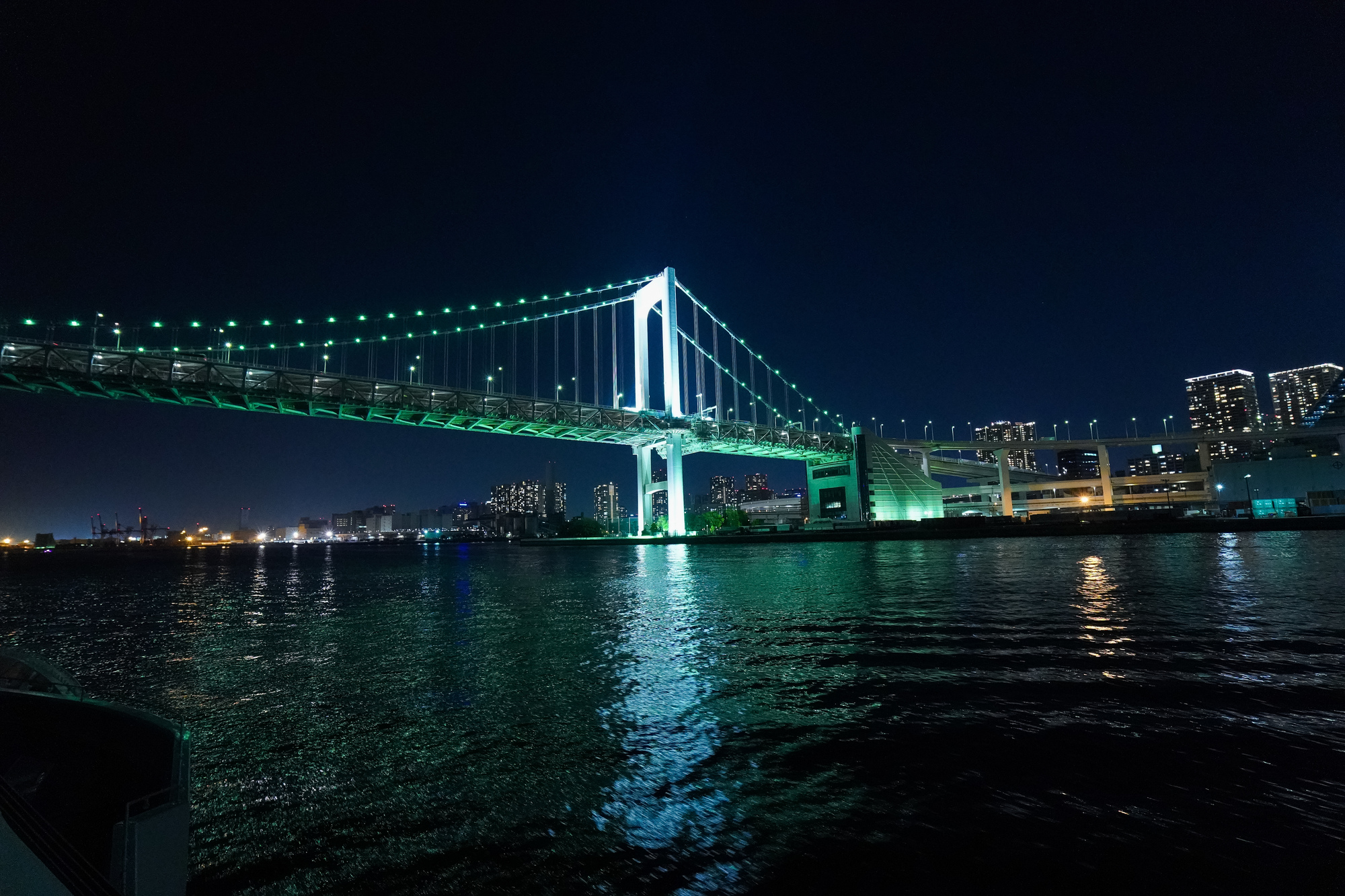 海の上から見るライトアップされた橋と川岸の夜景