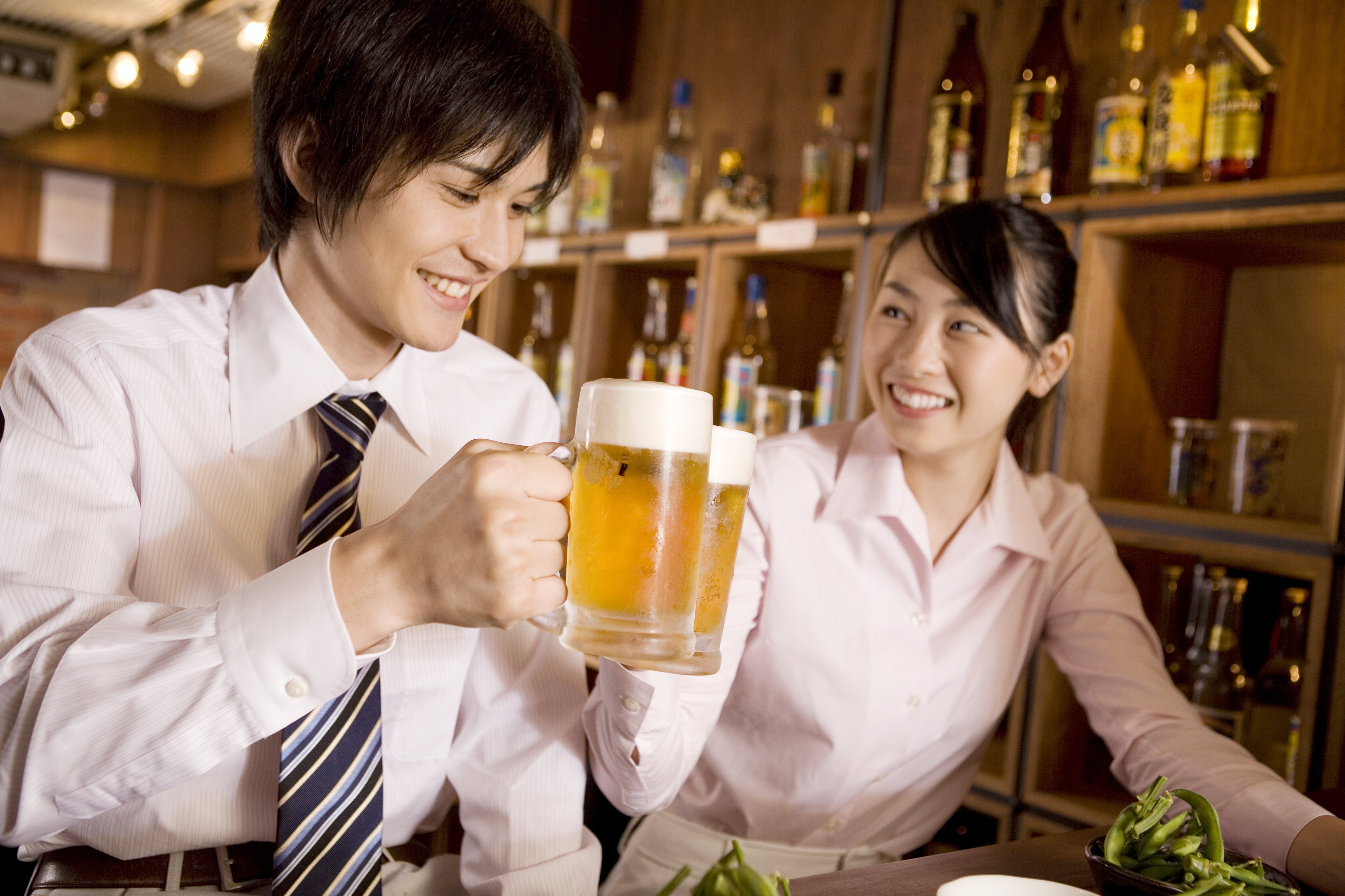 ビールで乾杯しているスーツの男女