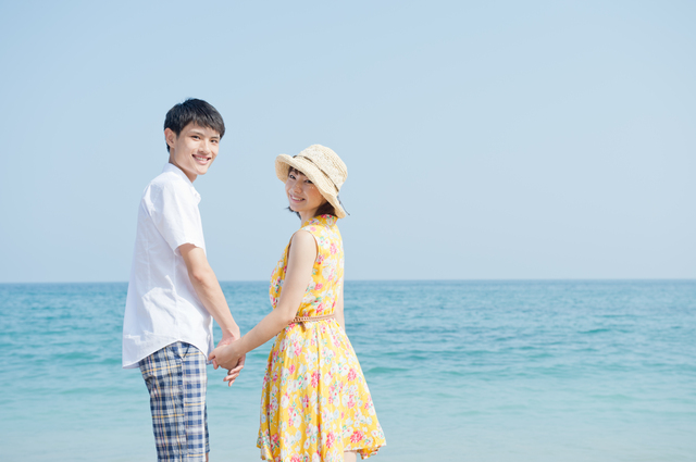 海辺で手をつないでいる男女