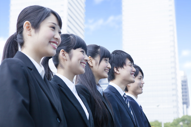 スーツを着て笑顔で並ぶ若い男女のグループ