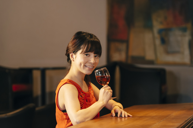 ワインが入ったグラスを持って微笑む女性