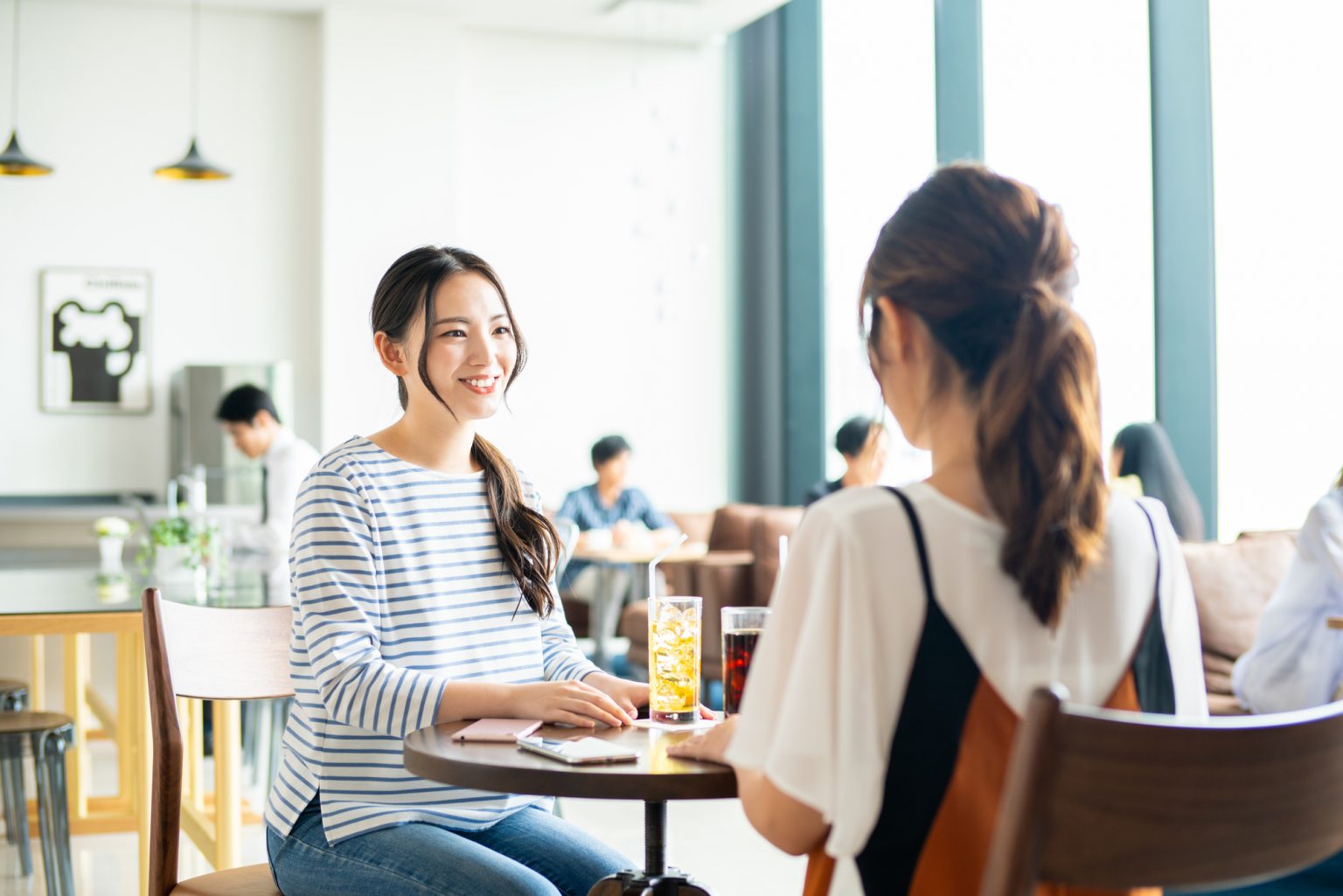 テーブルで飲物を飲みながら話す二人の女性