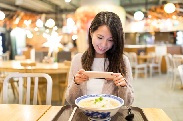 ラーメンの写真を撮る女性