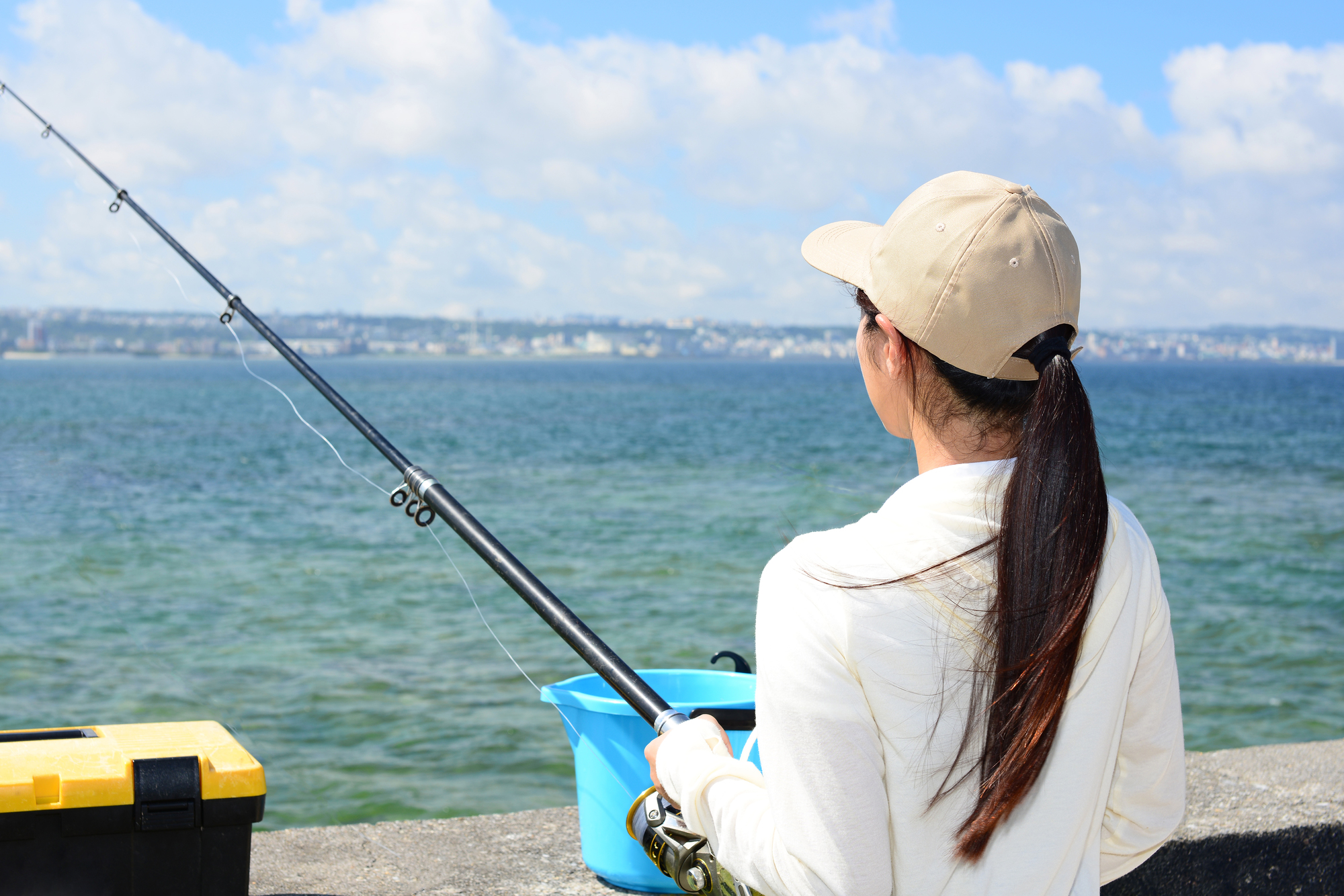 堤防から釣りを楽しんでいる女性