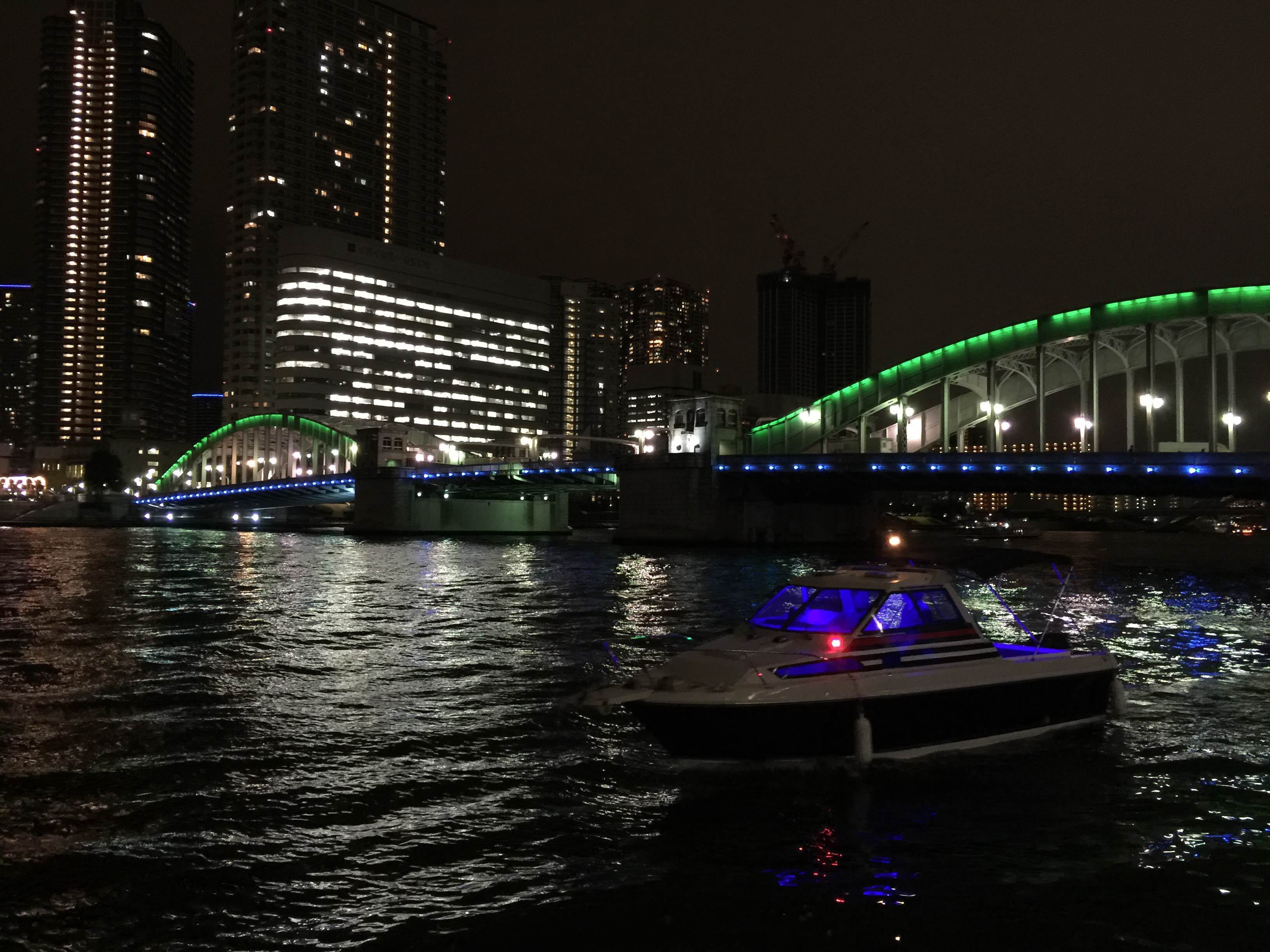 LEDで装飾された小型船とライトアップされた夜の橋
