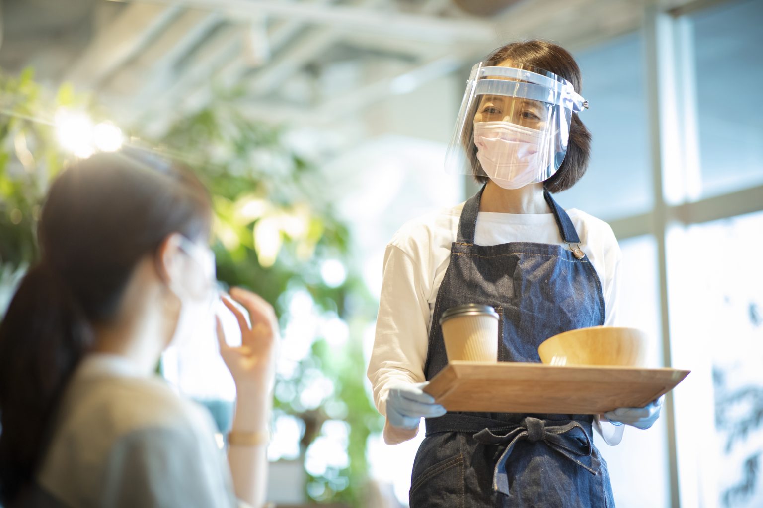 フェイスシールドで接客する女性