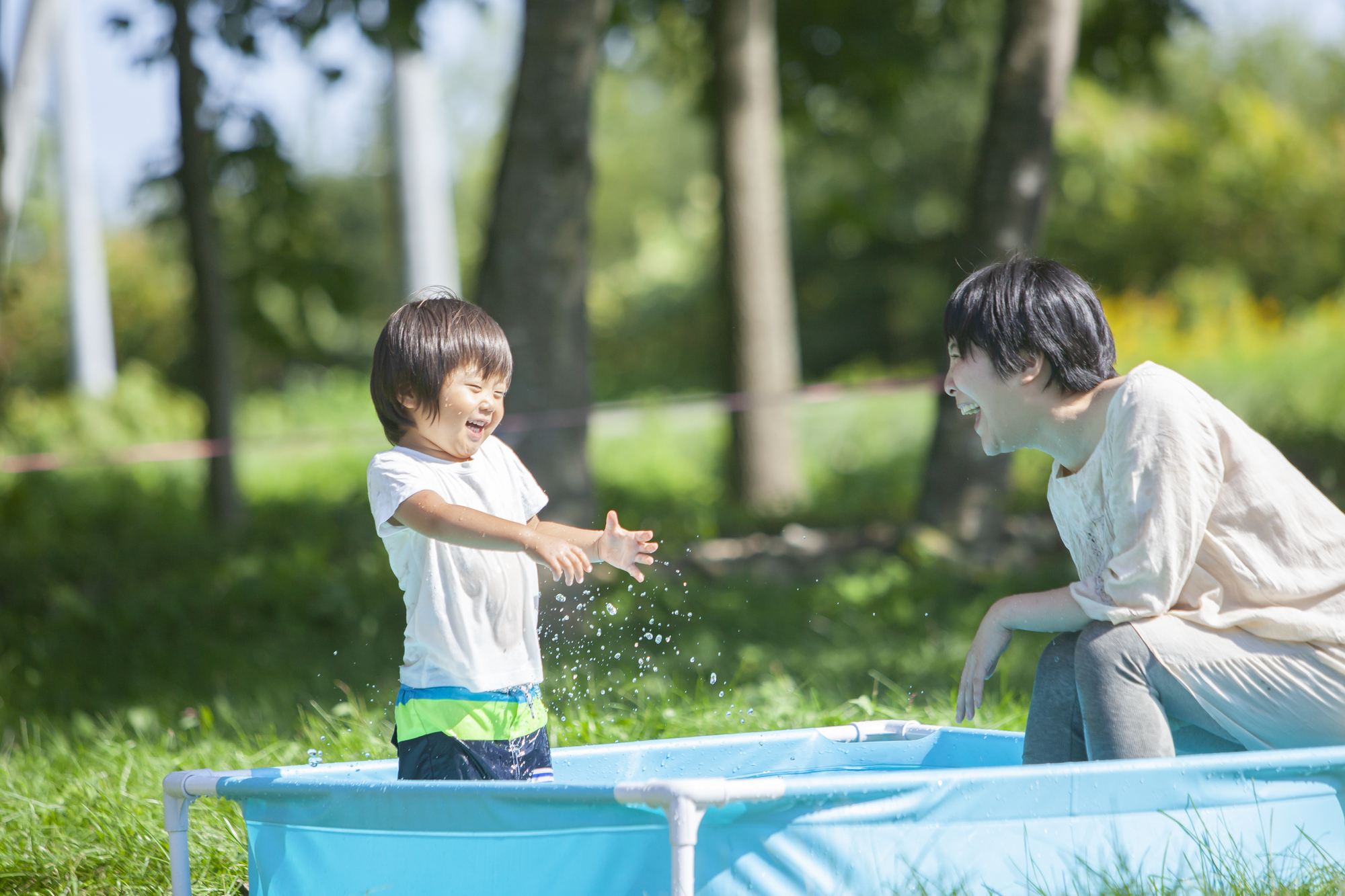 子どもと水遊びをしている親