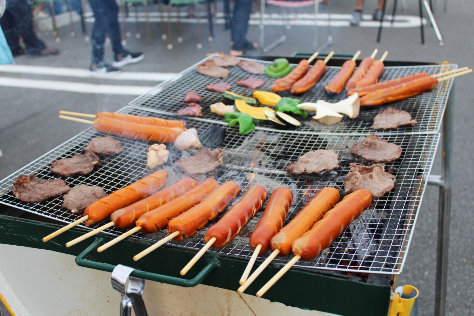 大きなグリルでたくさんの肉やウインナーを焼く