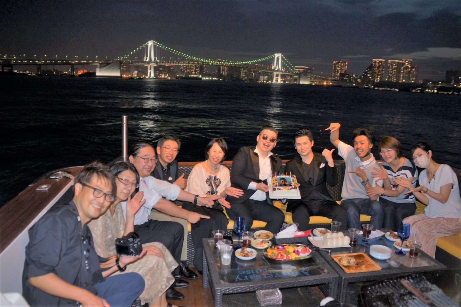 東京湾の輝く夜景を背景に集合写真を撮影する男女