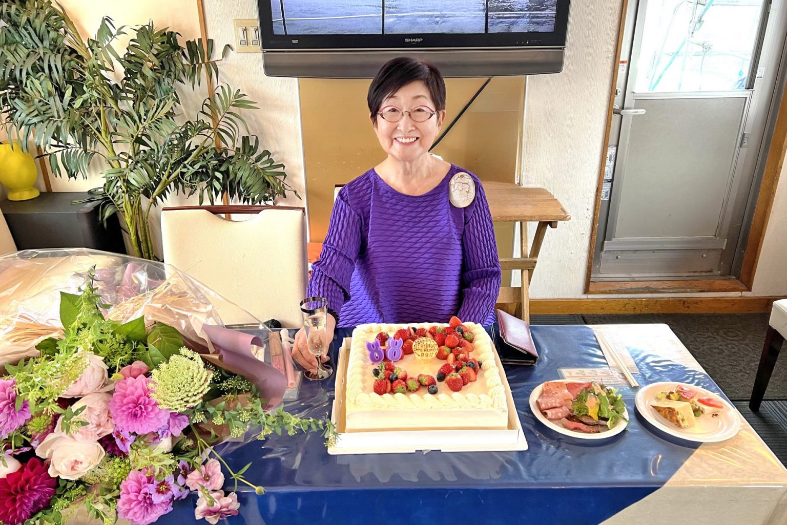 88歳のお祝いケーキと主役の女性が記念撮影をする様子
