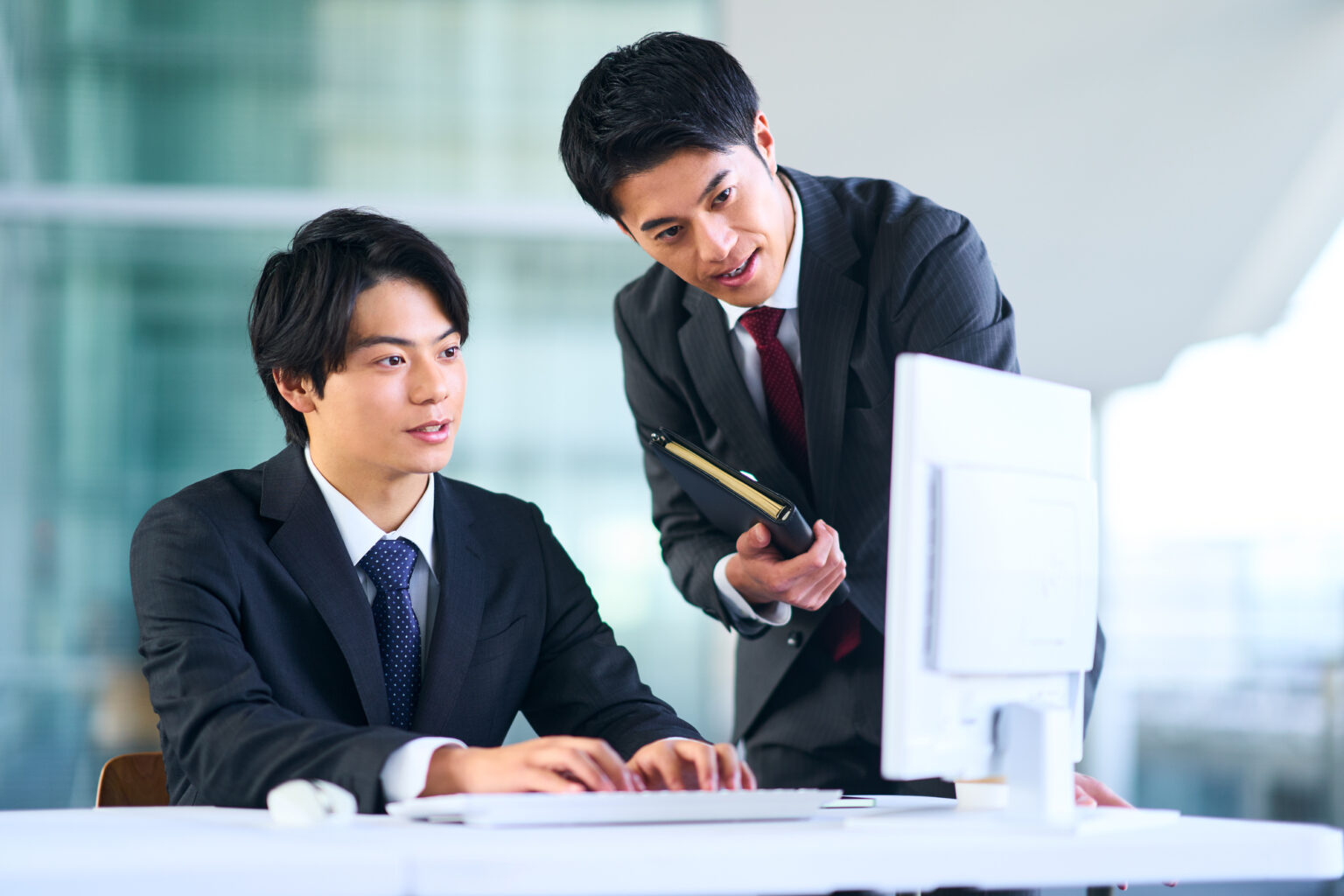 PCを見て相談する社員2人