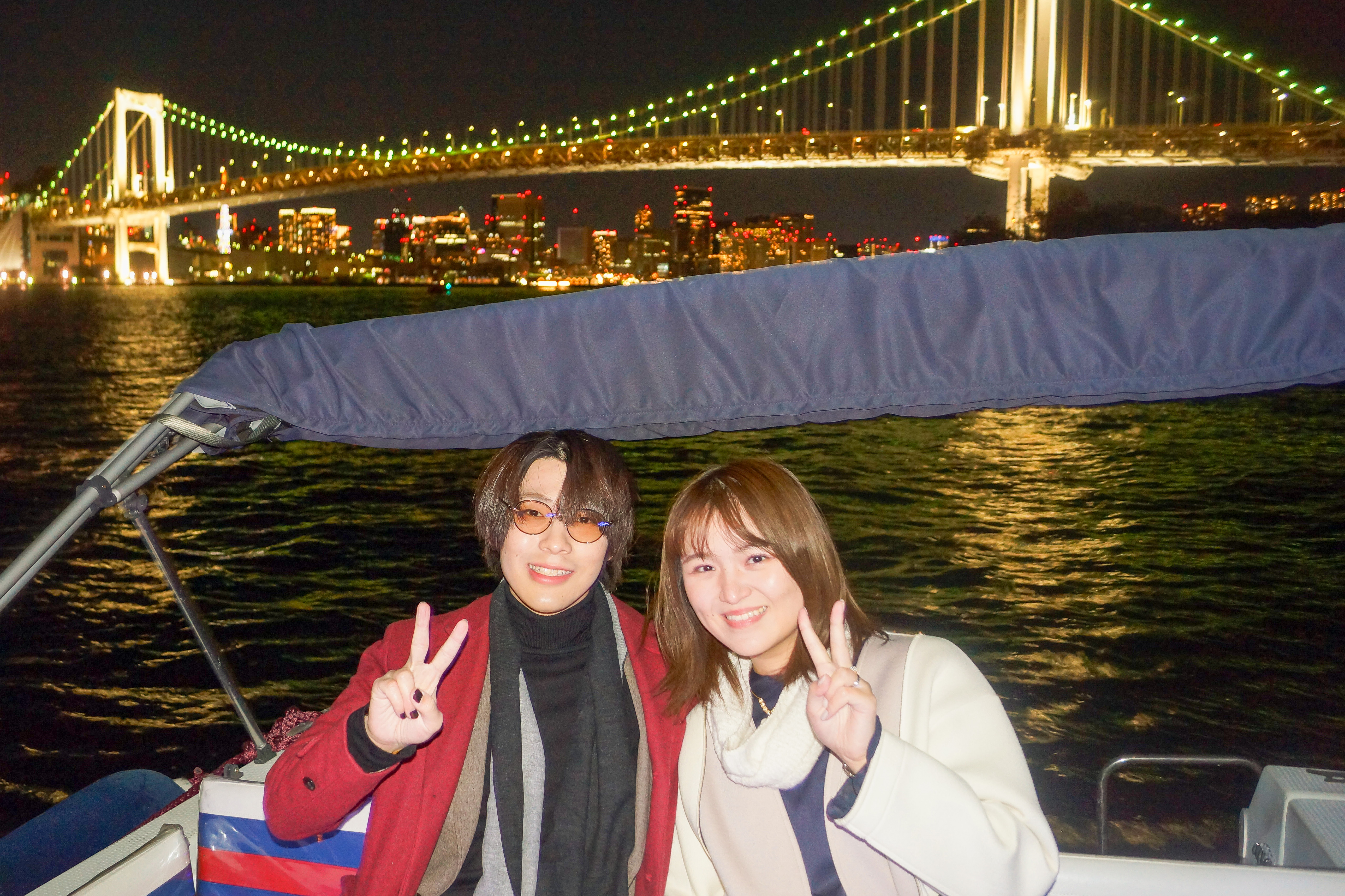 レインボーブリッジを背景に記念写真を撮るカップル