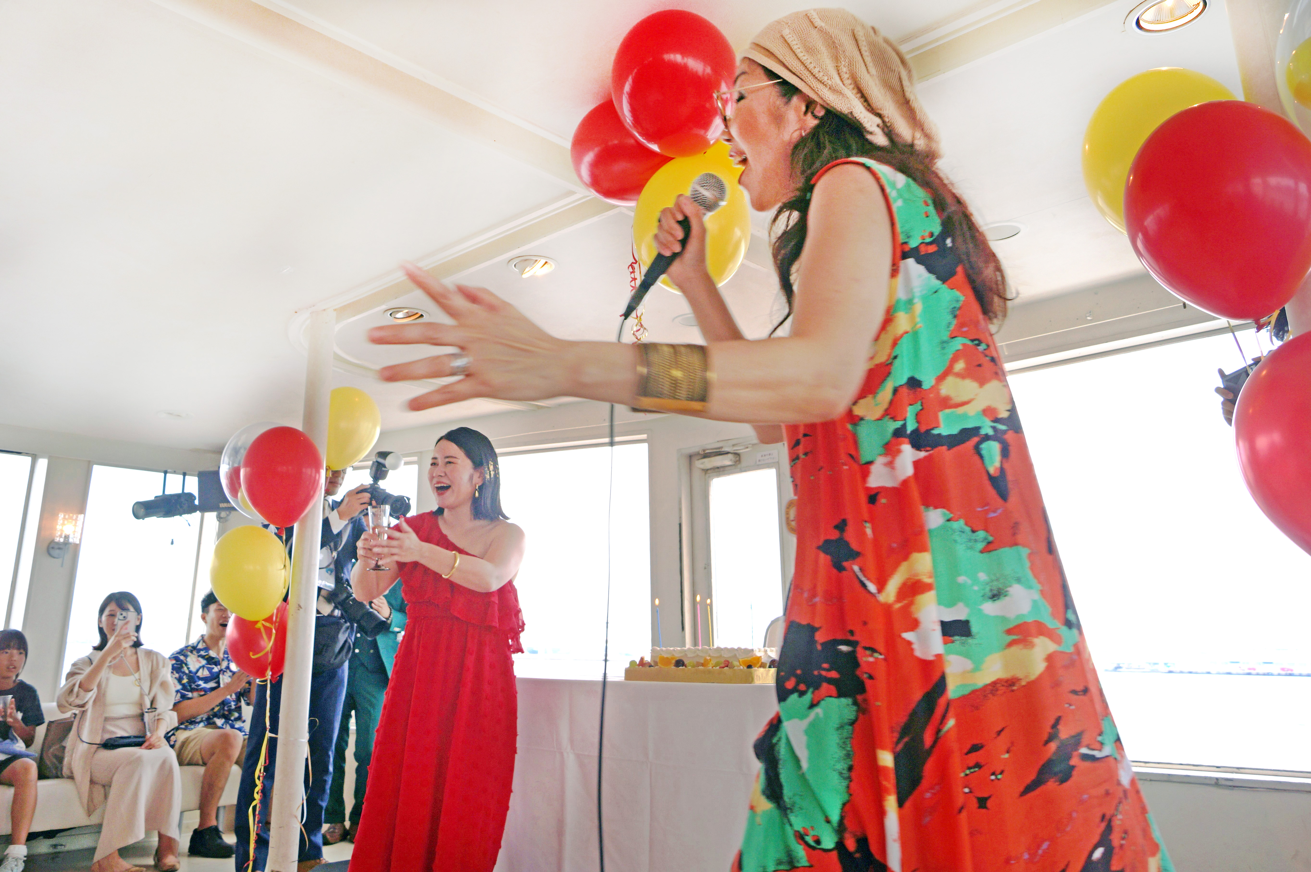 誕生日ケーキ登場をマイクでアナウンスする女性