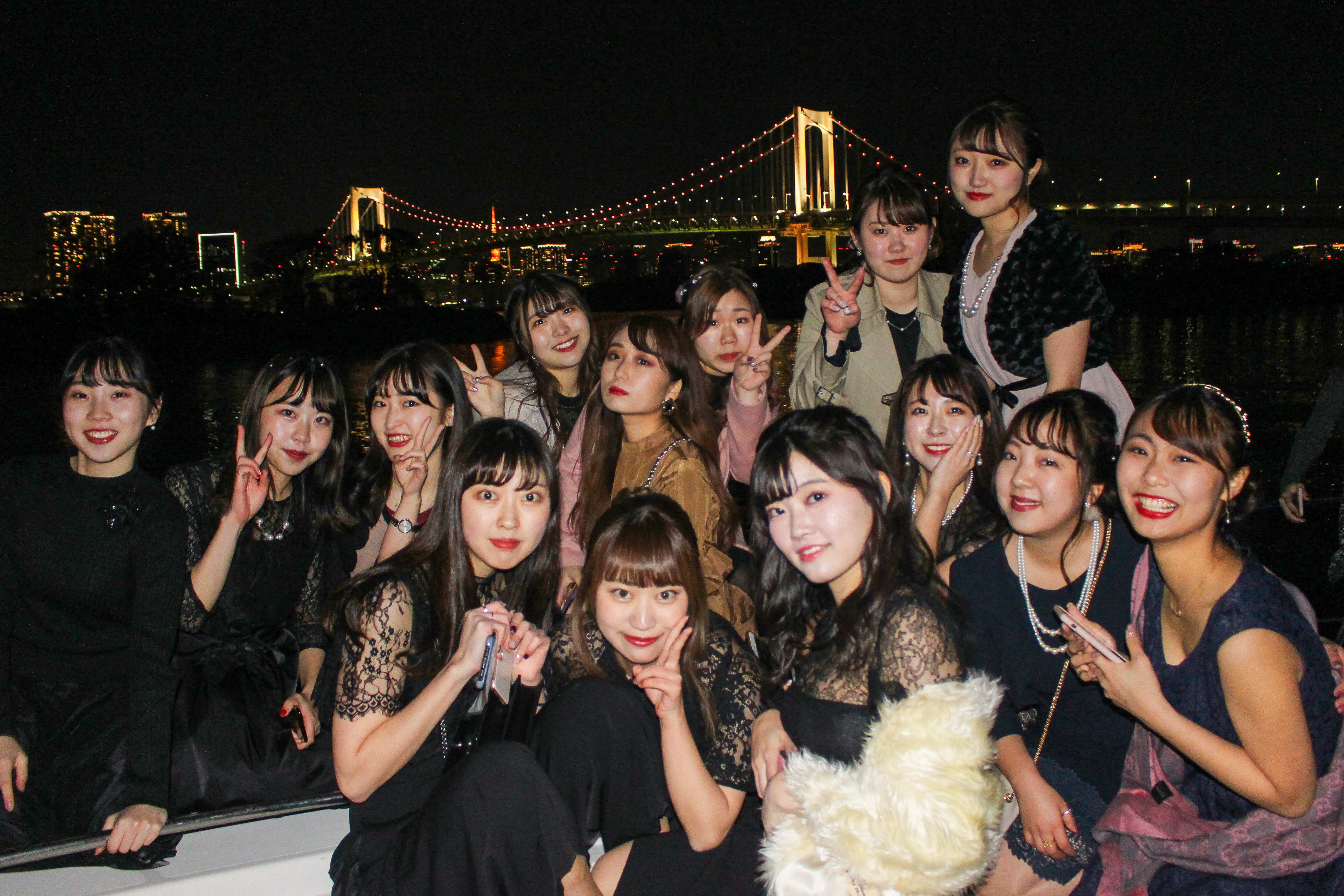 レインボーブリッジを背景に船で写真を撮る女の子たち