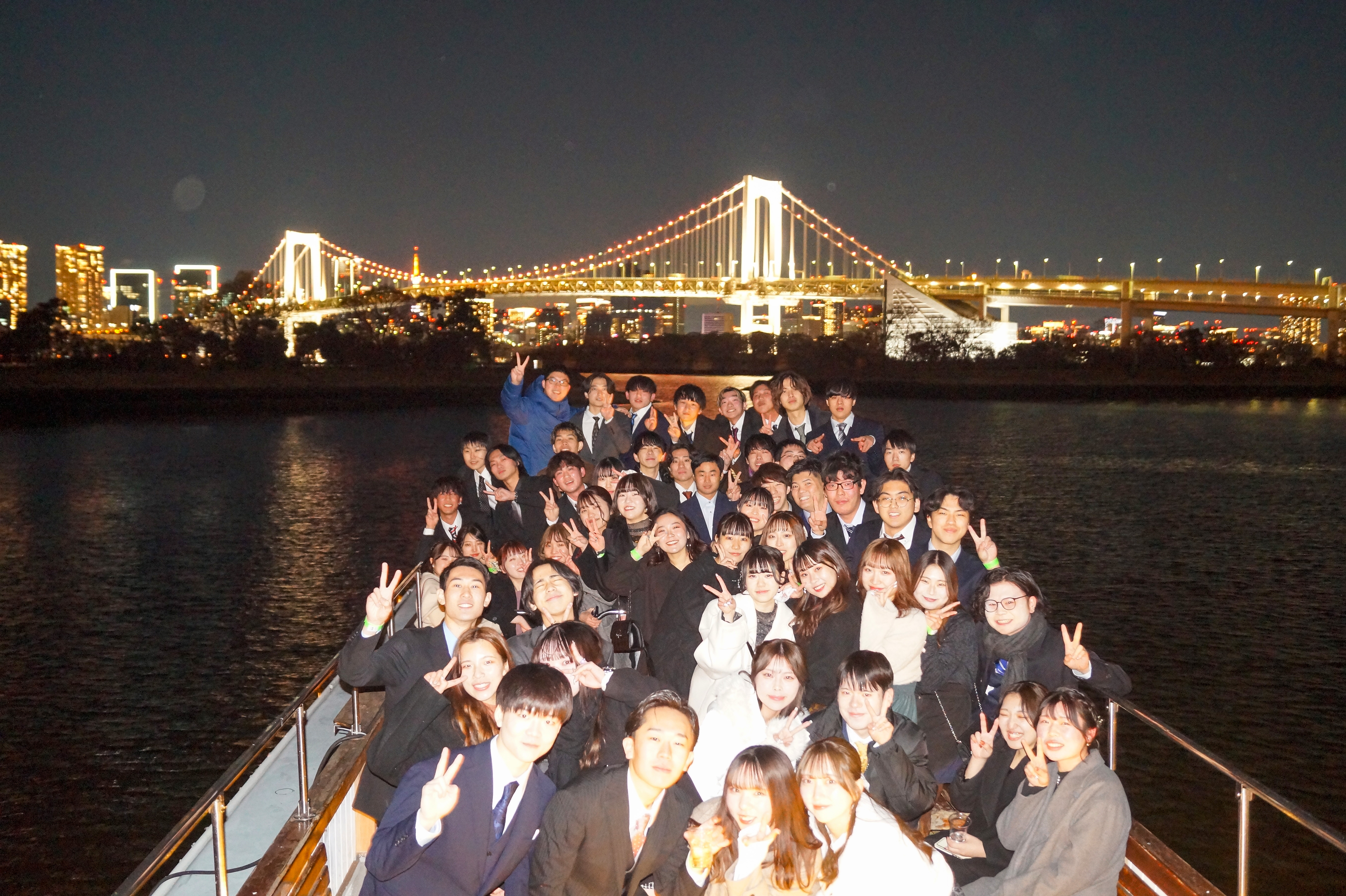 デッキでレインボーブリッジをバックに集合写真