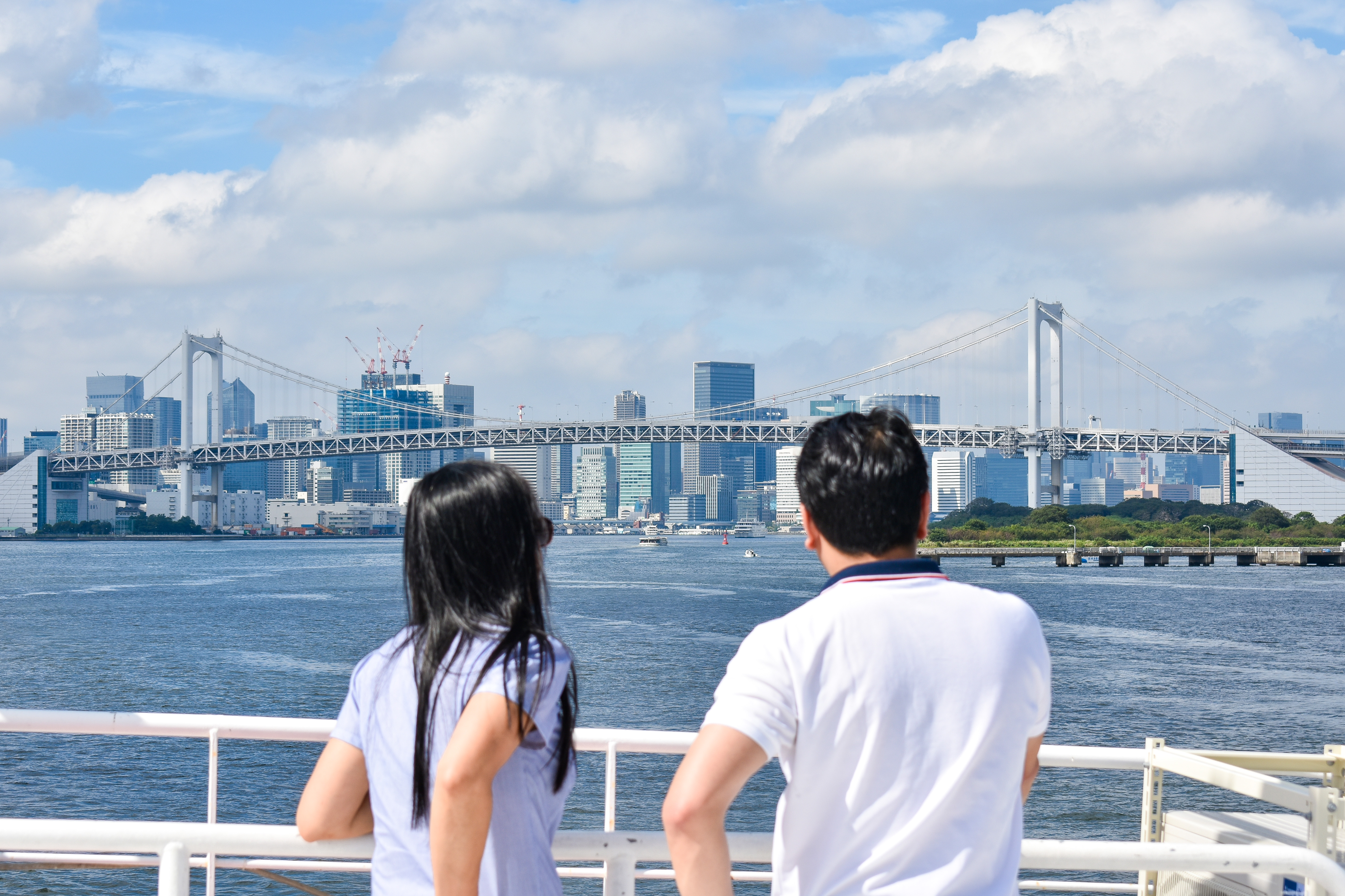 デッキでレインボーブリッジを眺めるカップルの後ろ姿