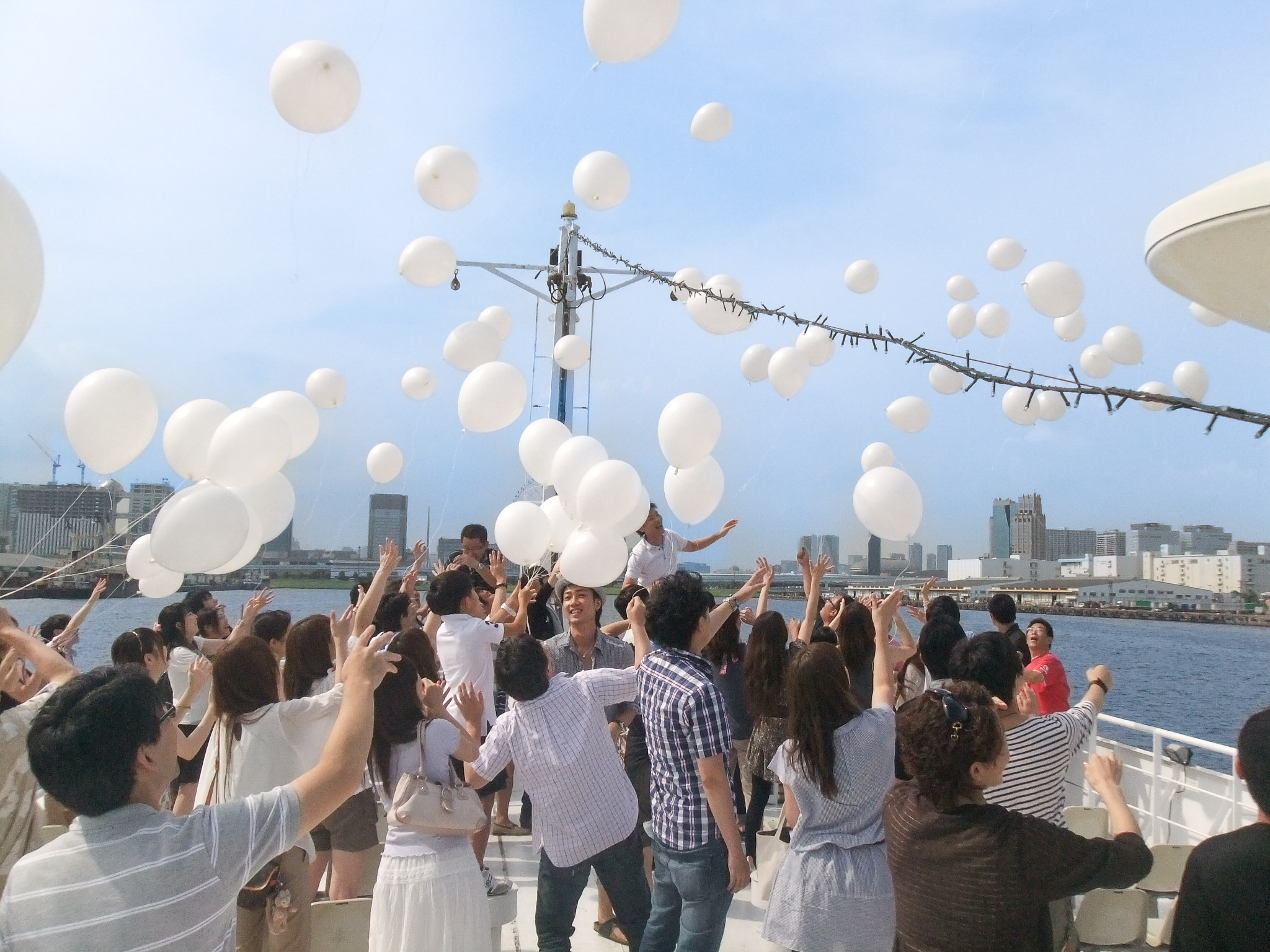 大型クルーザーの展望デッキでバルーンリリースを行う人たち