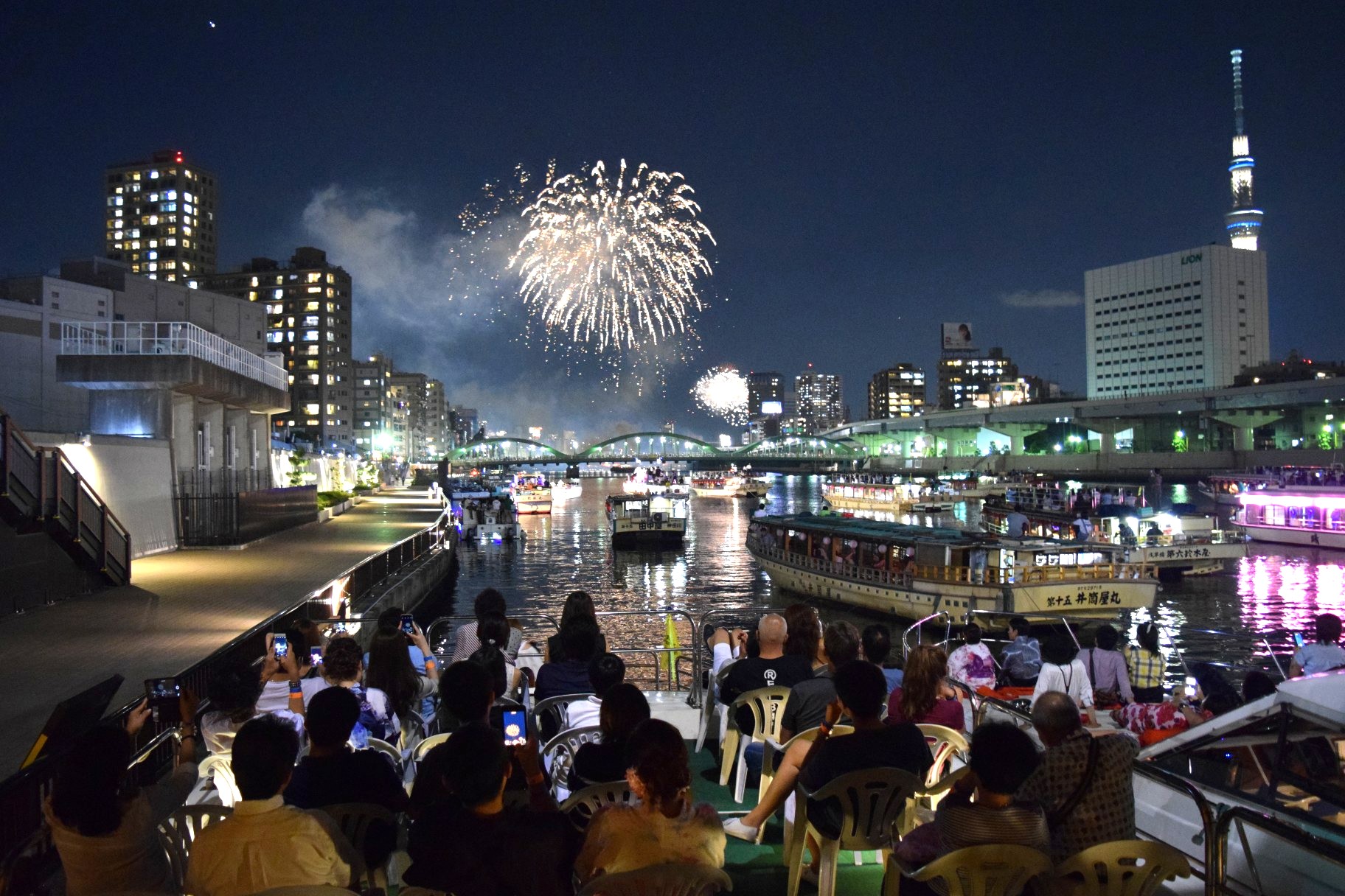 隅田川花火大会を船の2階デッキから眺める人々