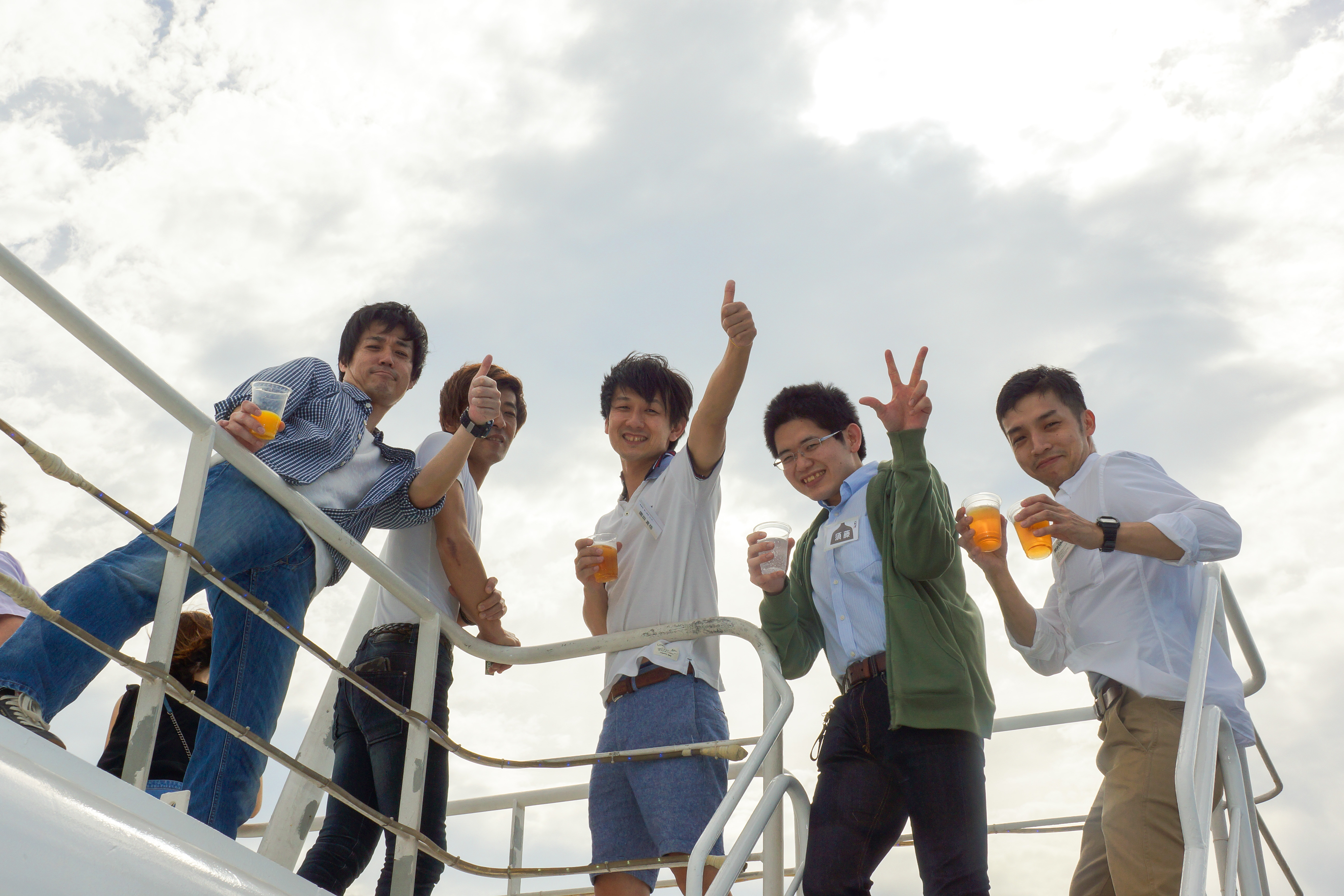 デッキでビール片手にポーズする男性たち