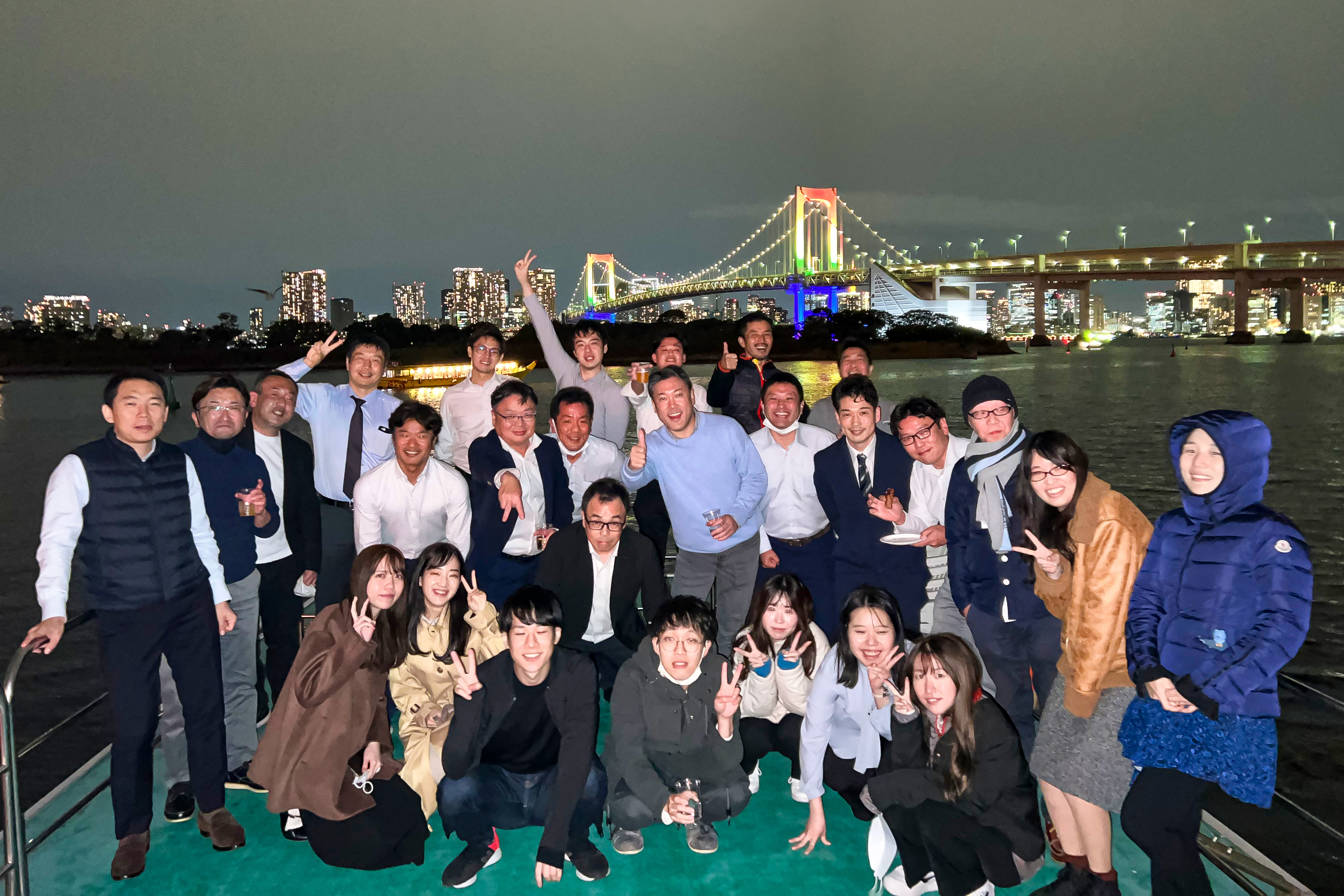 デッキでレインボーブリッジをバックに集合写真