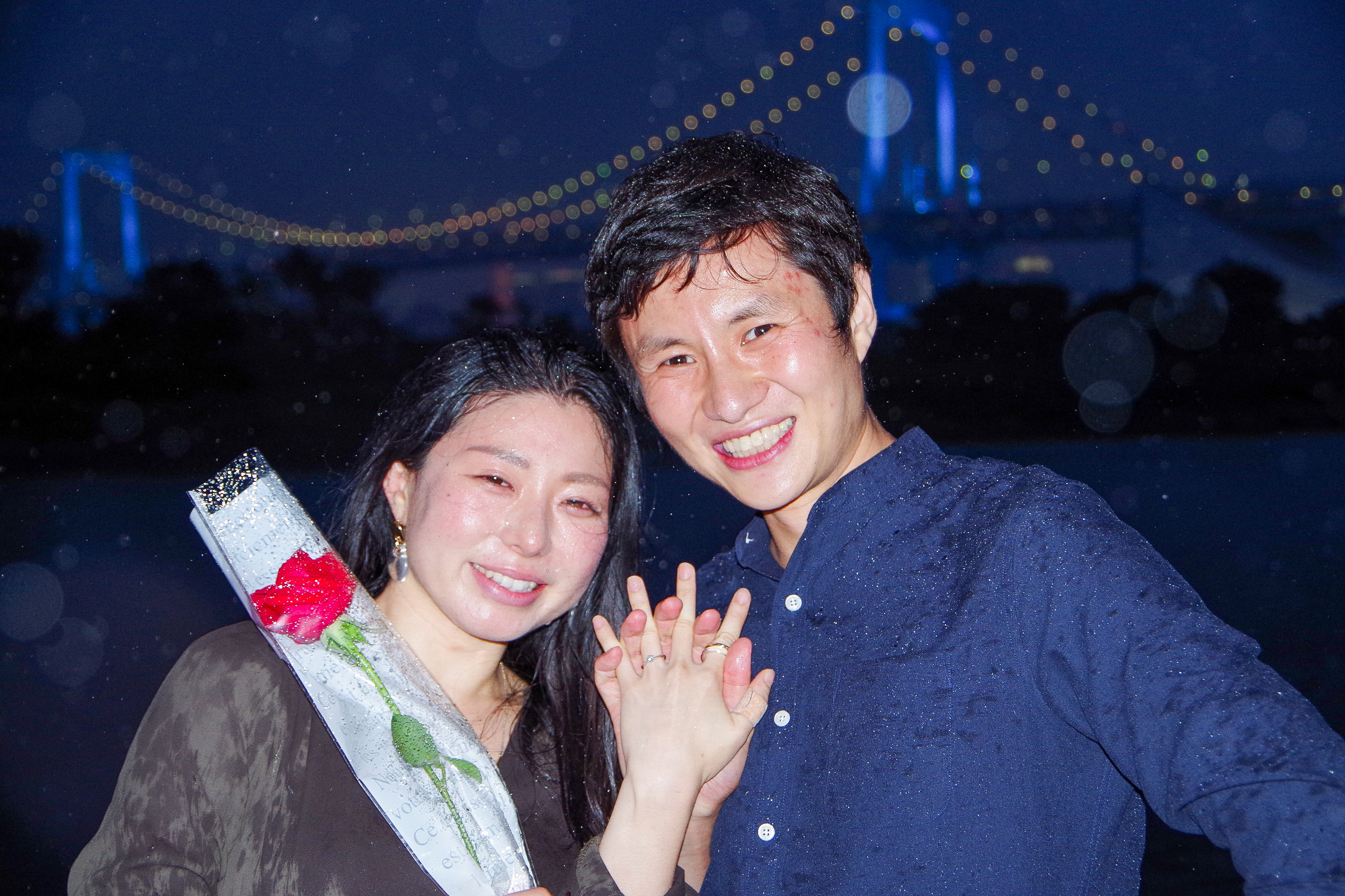 レインボーブリッジをバックにバラの花を持って記念撮影