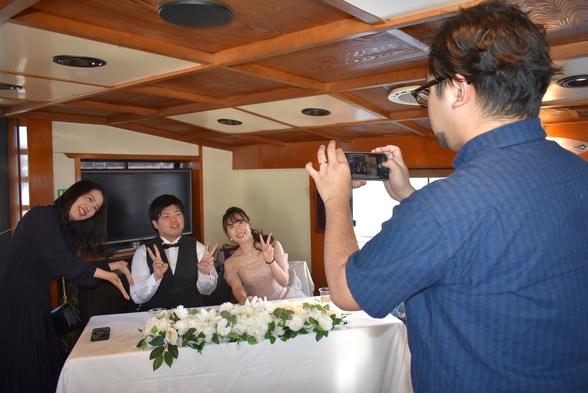 高砂席で記念撮影を楽しむ参加者と新郎新婦